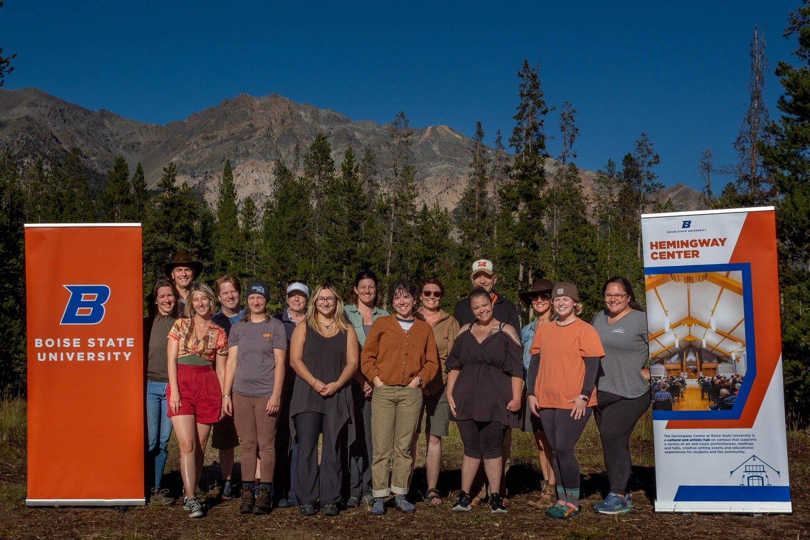 Participants in the Sawtooth Writing Retreat 2023 posing in front of a forest and mountain in the Sawtooth Mountain Range.