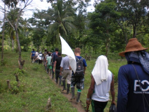 A group of people hike through a jungle trail