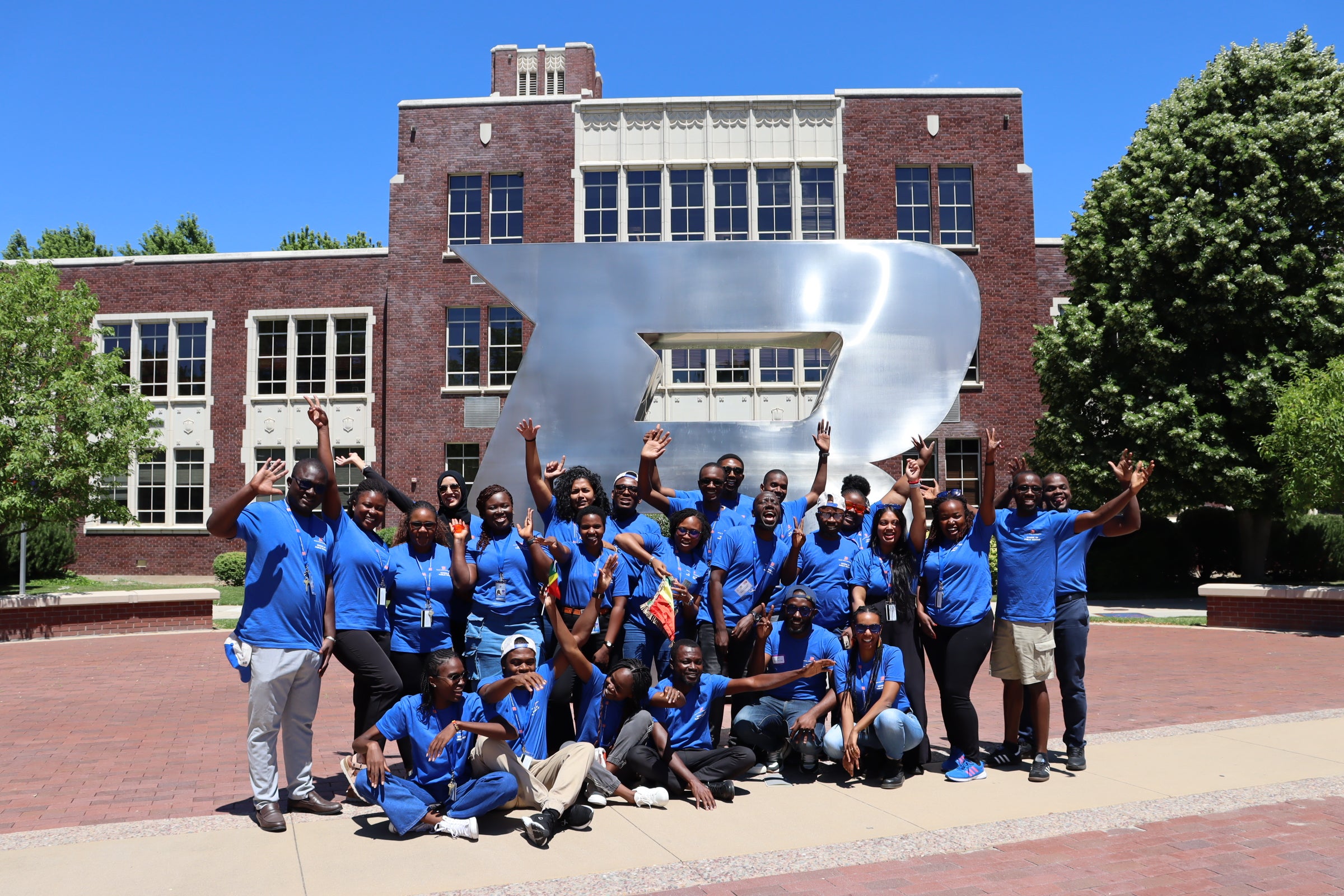 A group of persons pose in front of the Boise B statue
