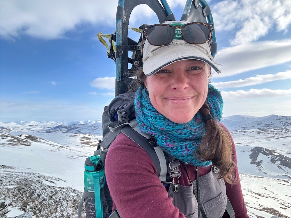 woman hiking with large back pack in snowy mountainous region