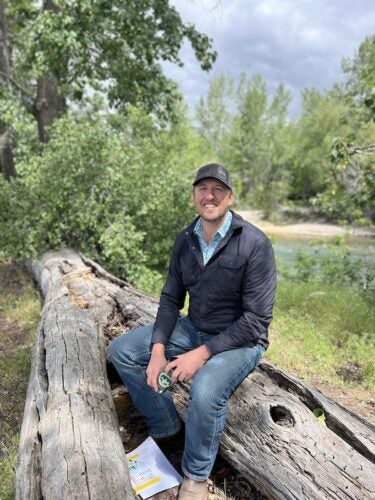 man sits on logs by river