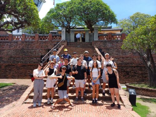 A group of students stands in front of a large set of brick steps, which are part of a fort built in the 1600s.