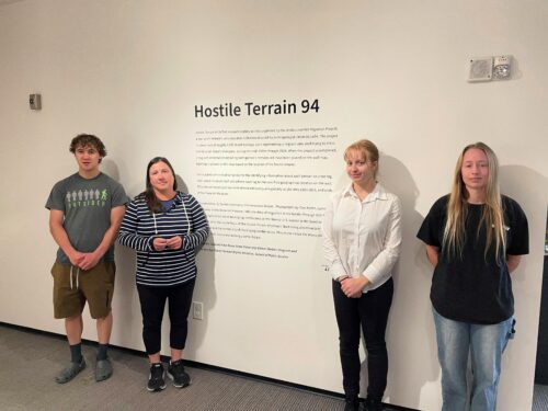 Students pose in front of an art exhibit