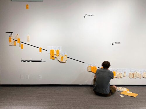 Student sits in front of a wall hanging art