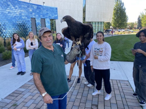 Monte Tish, a raptor expert, pictured with students and his golden eagle, Slim. 