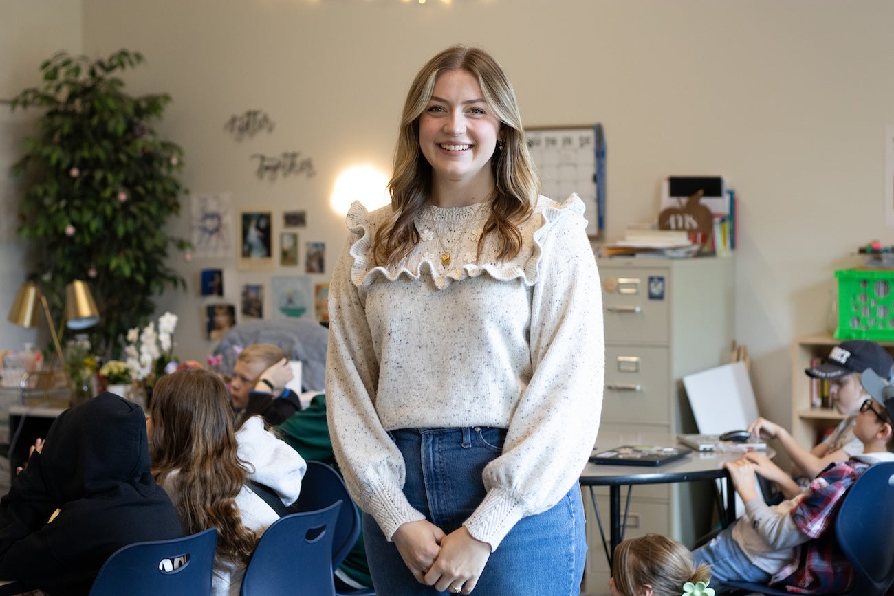 A teacher poses in her classroom