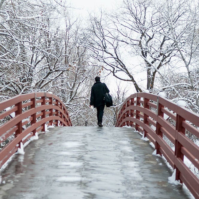 A man walks across the bridge from Boise State to Julia Davis Park in solitude