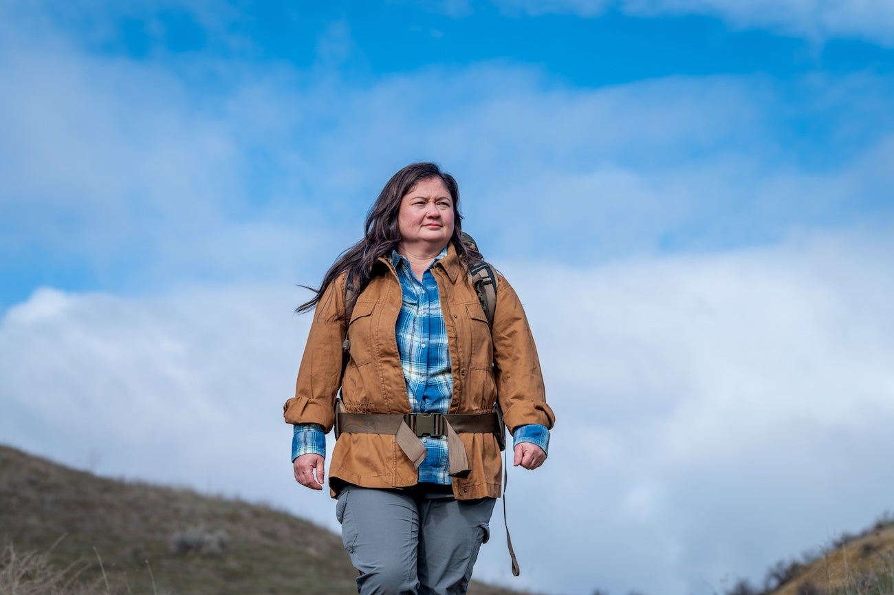 A person stands outdoors against a blue sky