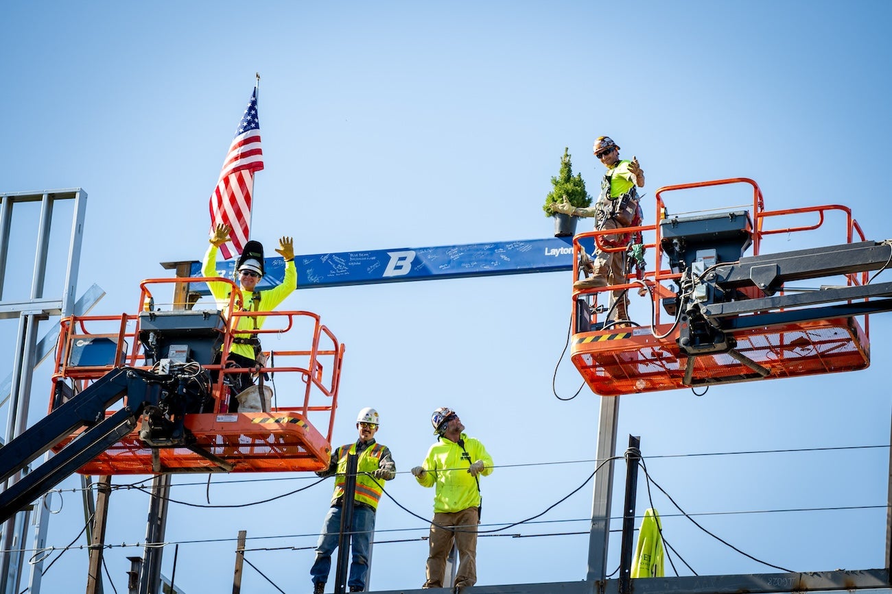 Workers raise a ceremonial beam into place