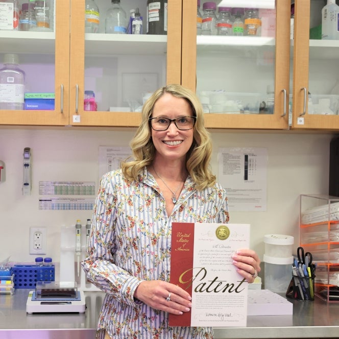 Stephanie Hudson stands in her lab holding her official new patent