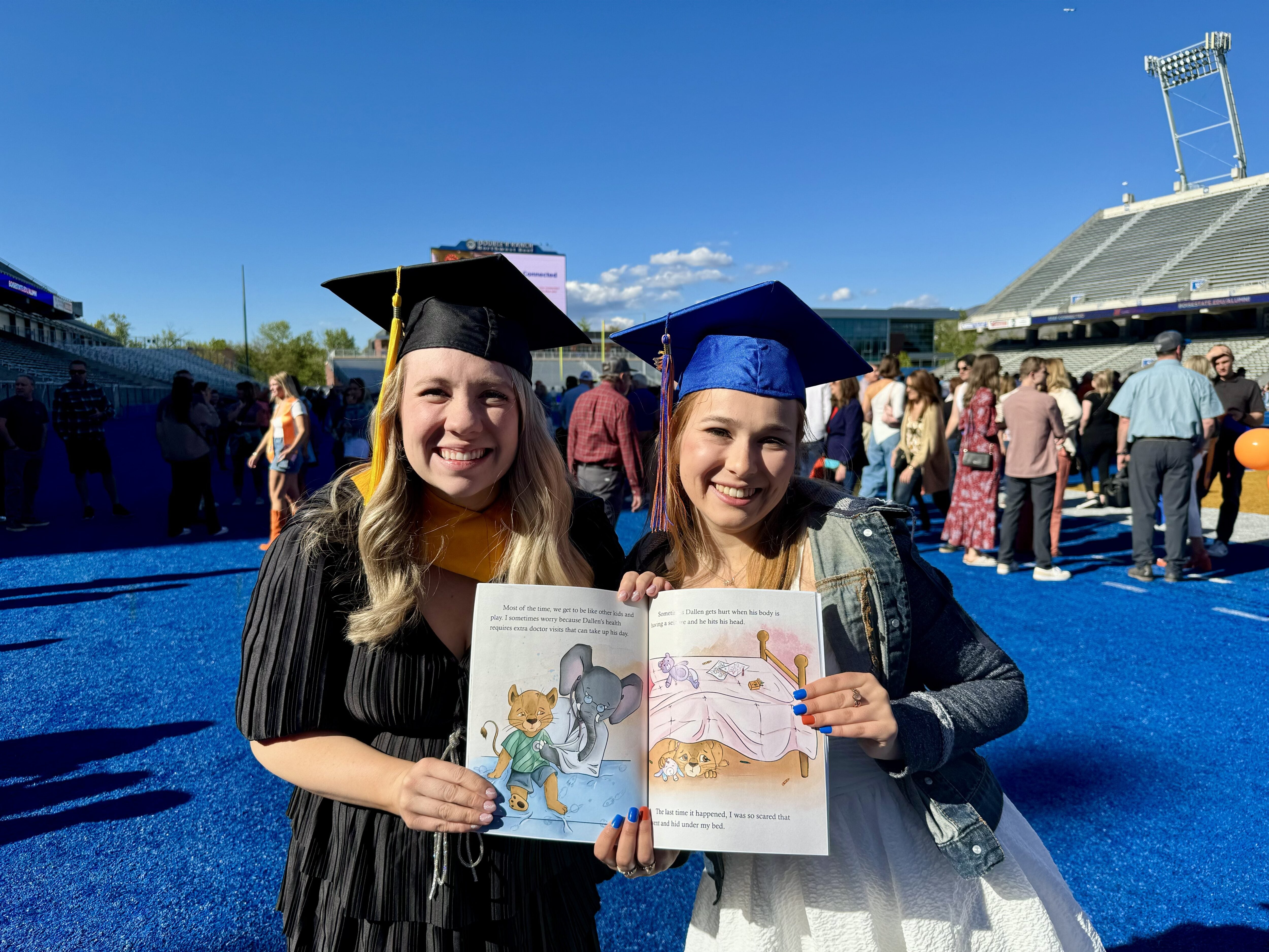 Two persons in regalia display a picture book