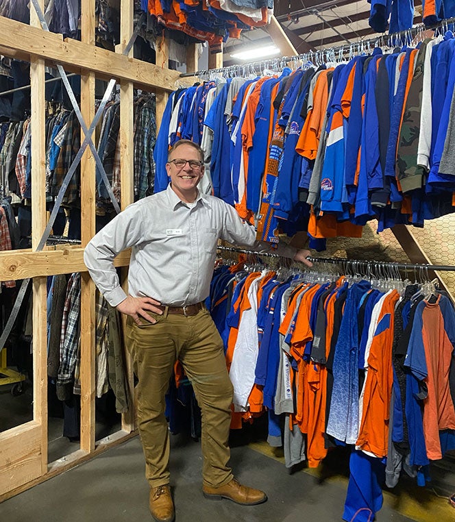 Scott Curtis poses in with Boise State shirts in distribution center