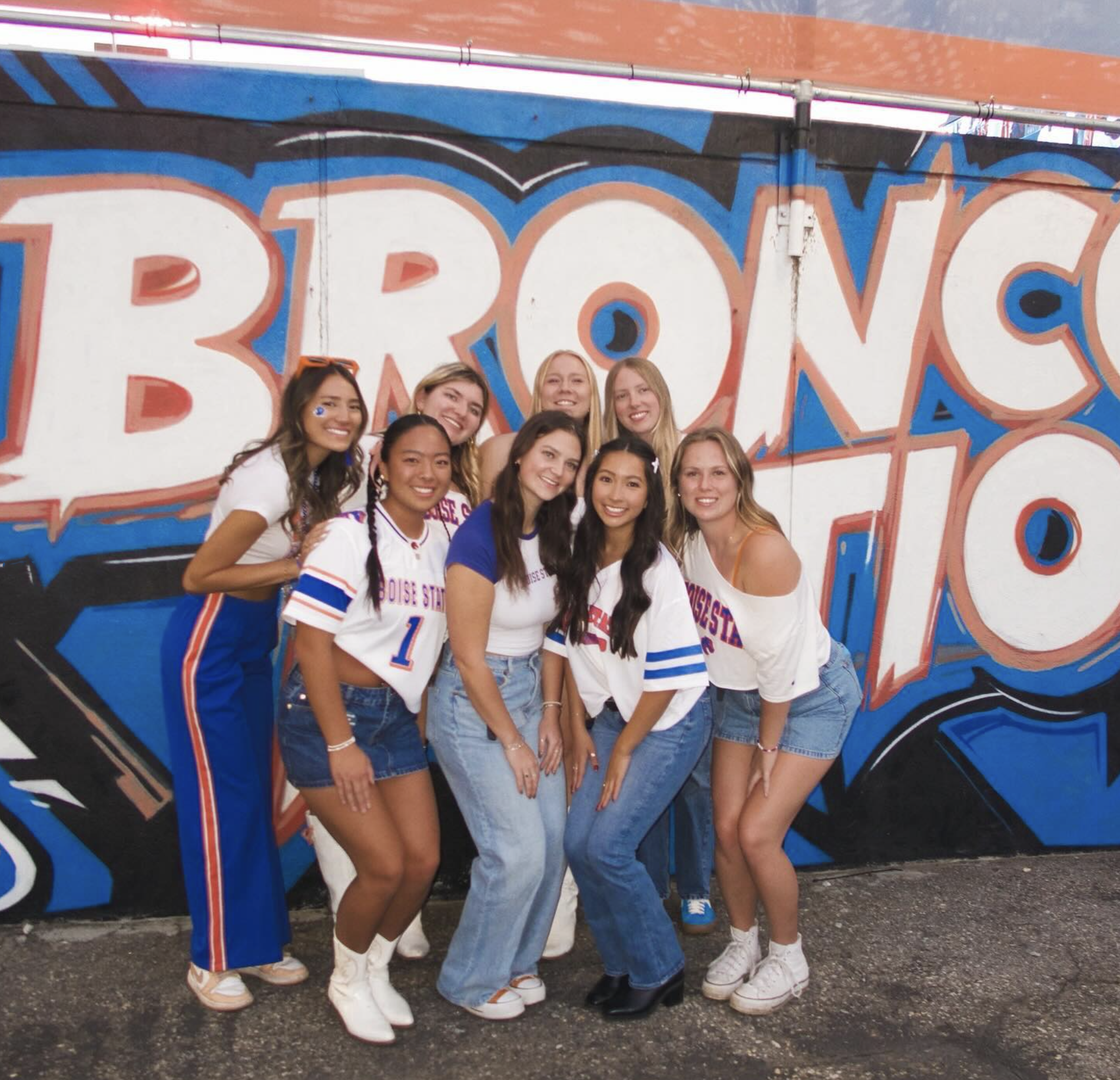 A group of persons pose in Boise State Broncos gear