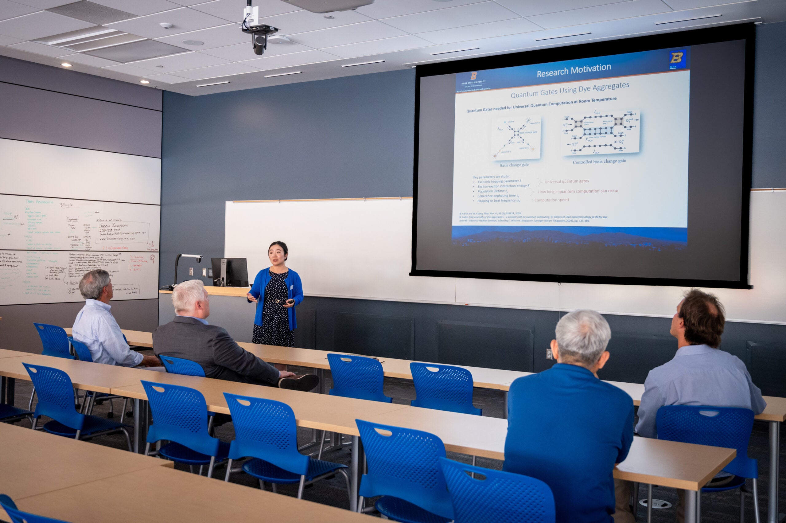 Professor presents in front of audience of four in a classroom.