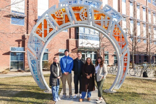 A group of persons poses at the geothermal sculpture on Boise State's campus 