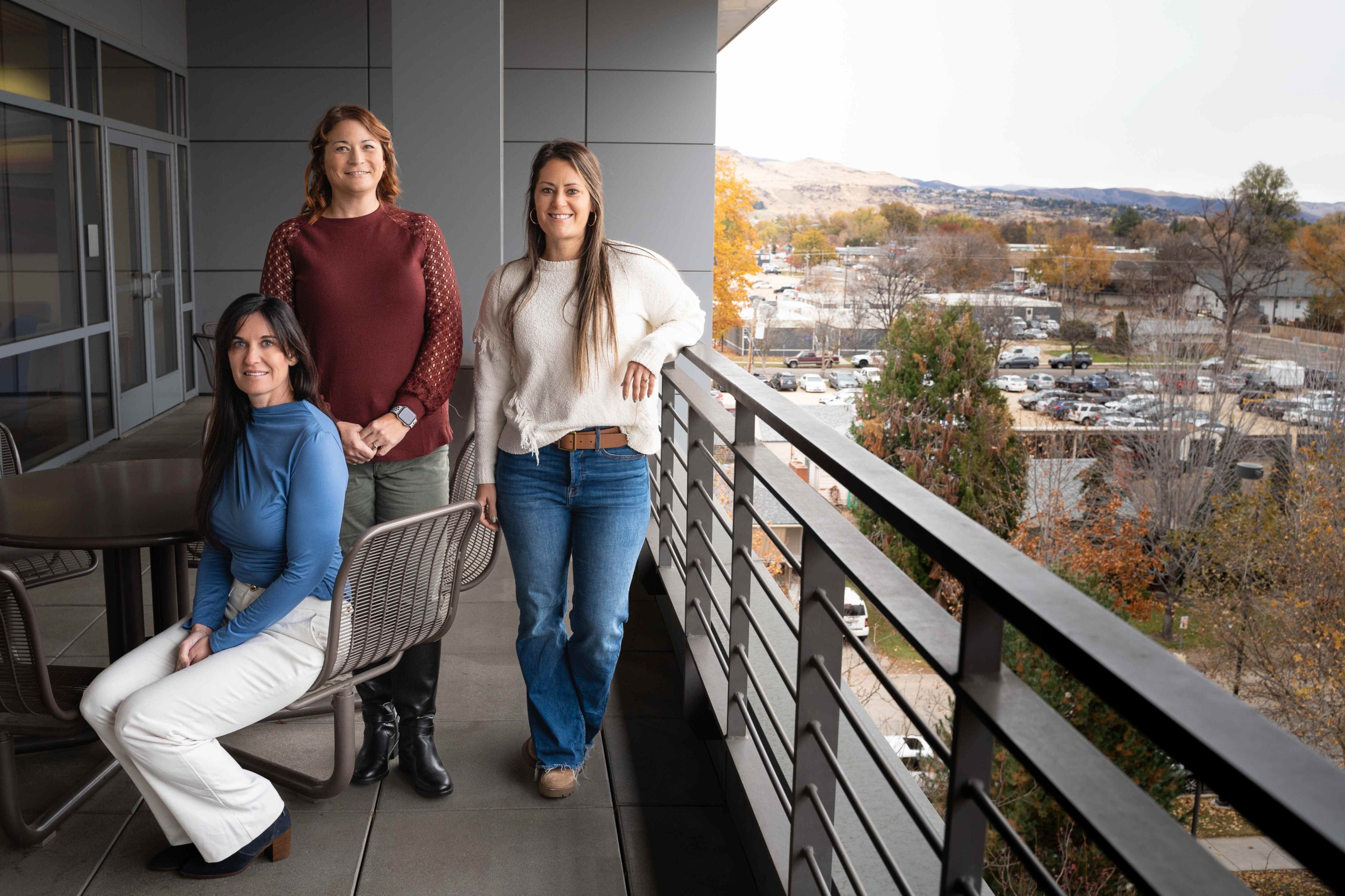 Jill Glenn, Tracee Chapman, and Chelsea Painter stand on the Norco building balcony overlooking Boise.