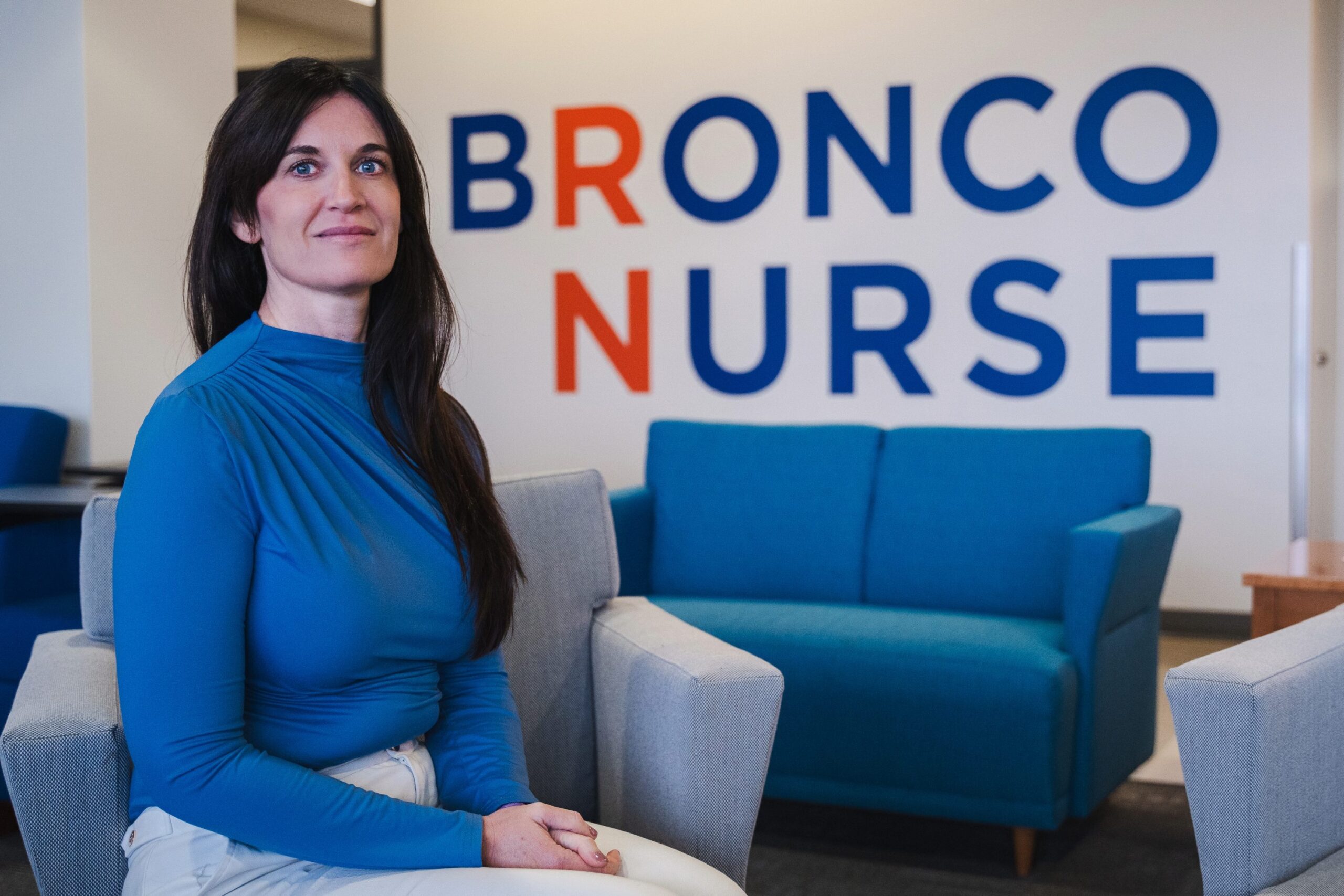 Jill Glenn sits in front of a wall that reads "Bronco Nurse".