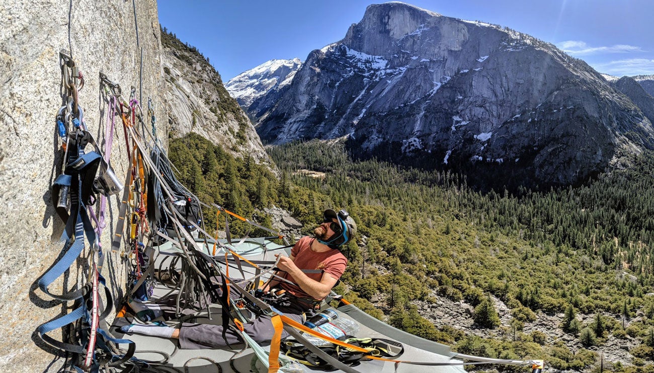 Dane Larson uses rock climbing gear to hang suspended on the side of a mountain.