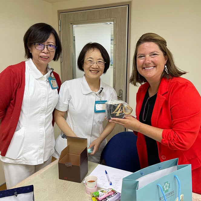 Walters holds a gift and smiles with to two nurses in Taiwan.