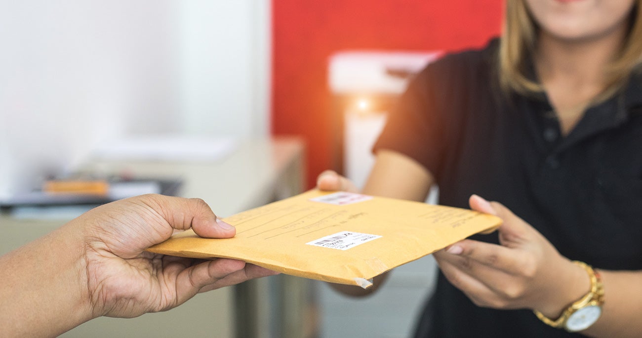 Person handing a mail delivery to another person