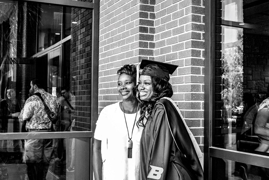 Patrice Elmore is pictured in a cap and gown alongside a family member.