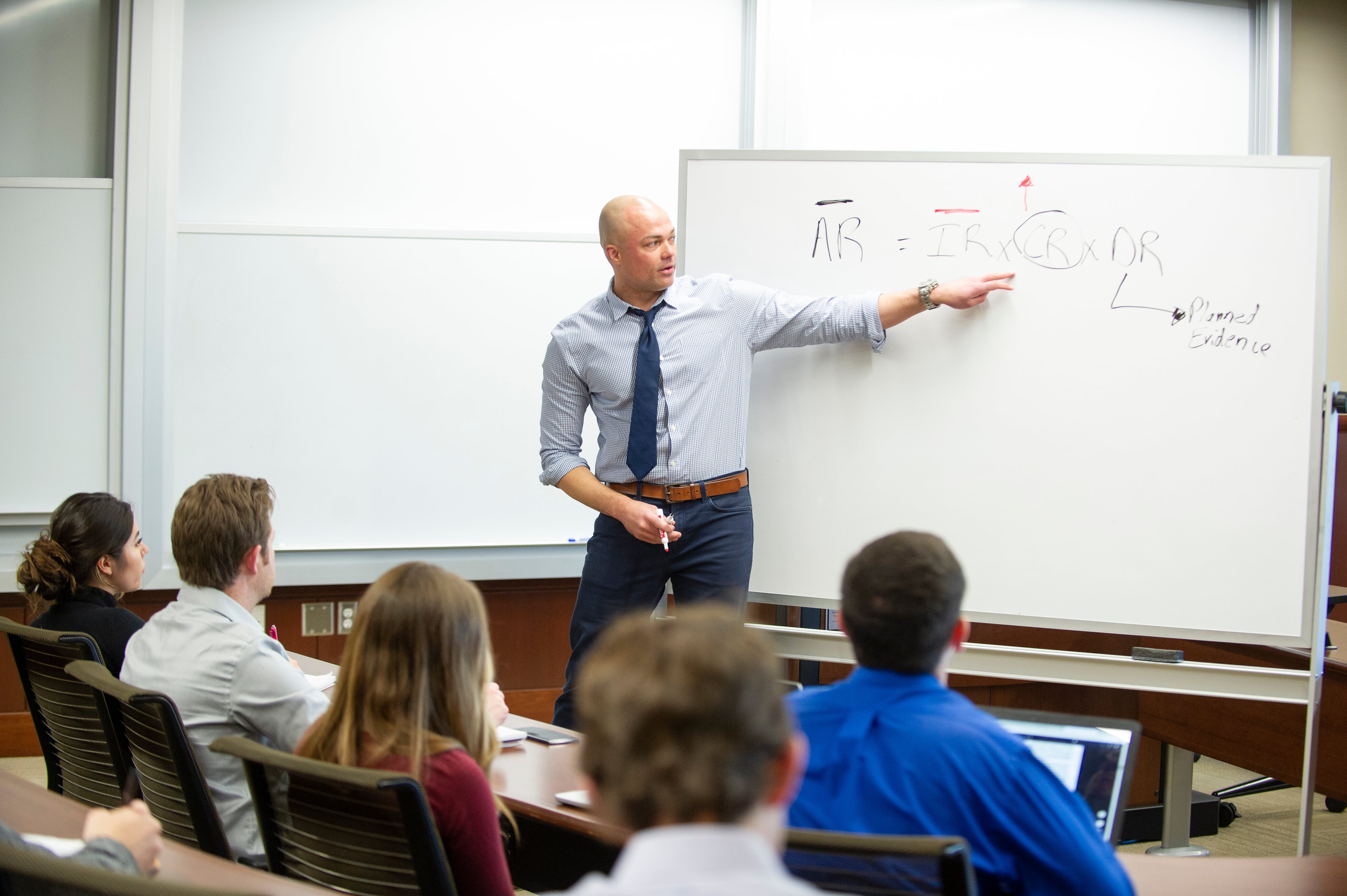 Eric Gooden stands at a whiteboard, teaching a class.