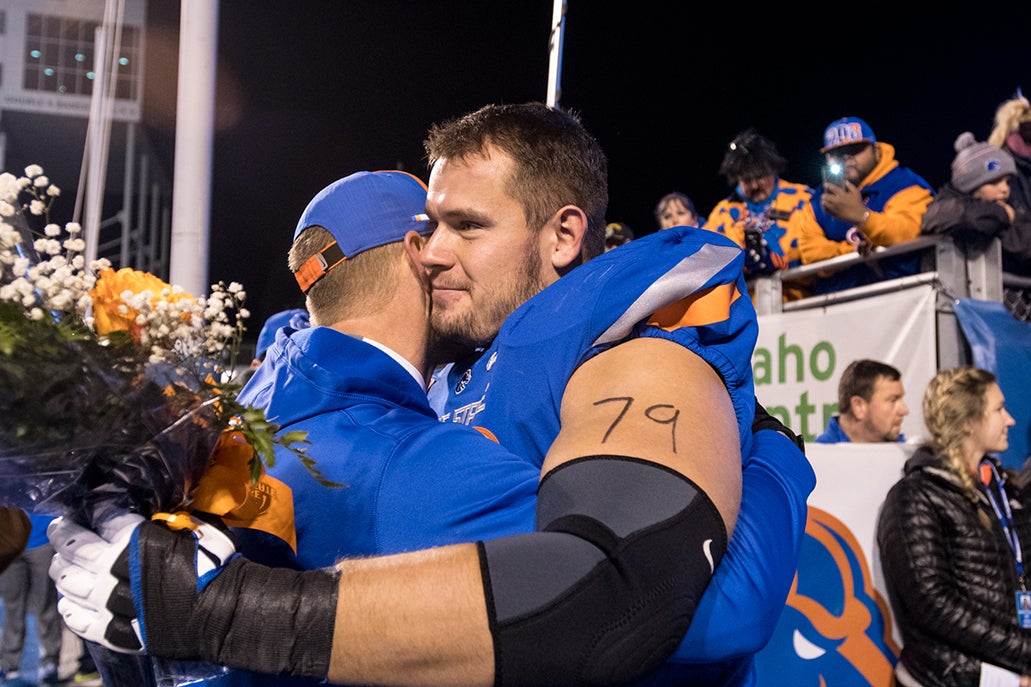 Mason Hampton dressed in football uniform, hugging coach. 