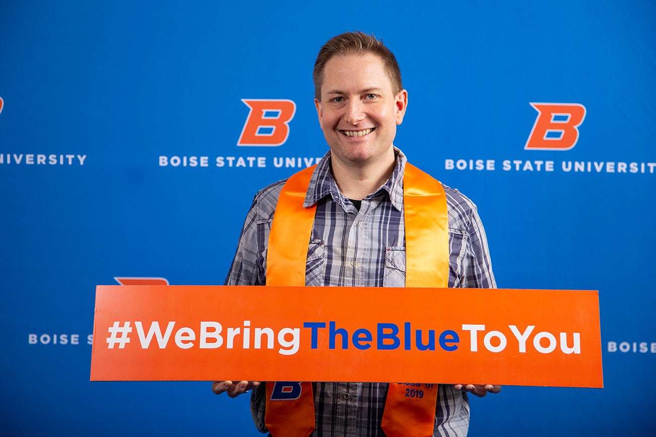 Student holds a sign reading "We Bring The Blue To You."