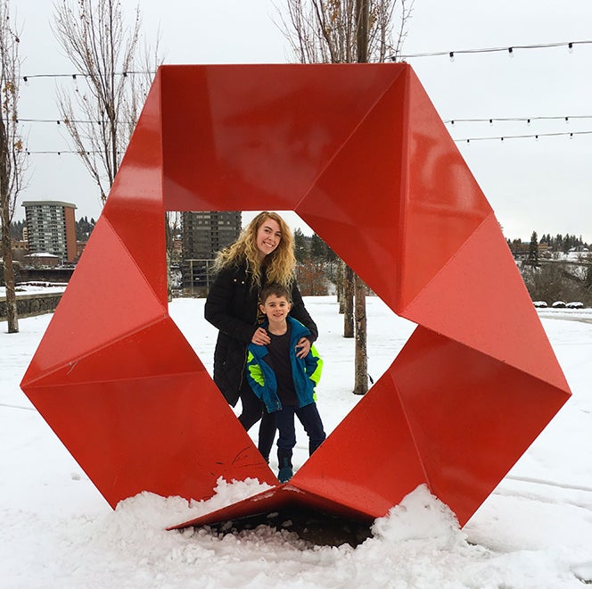 Meghan Howk and her son pose in the center of a red, oval-shaped sculpture.