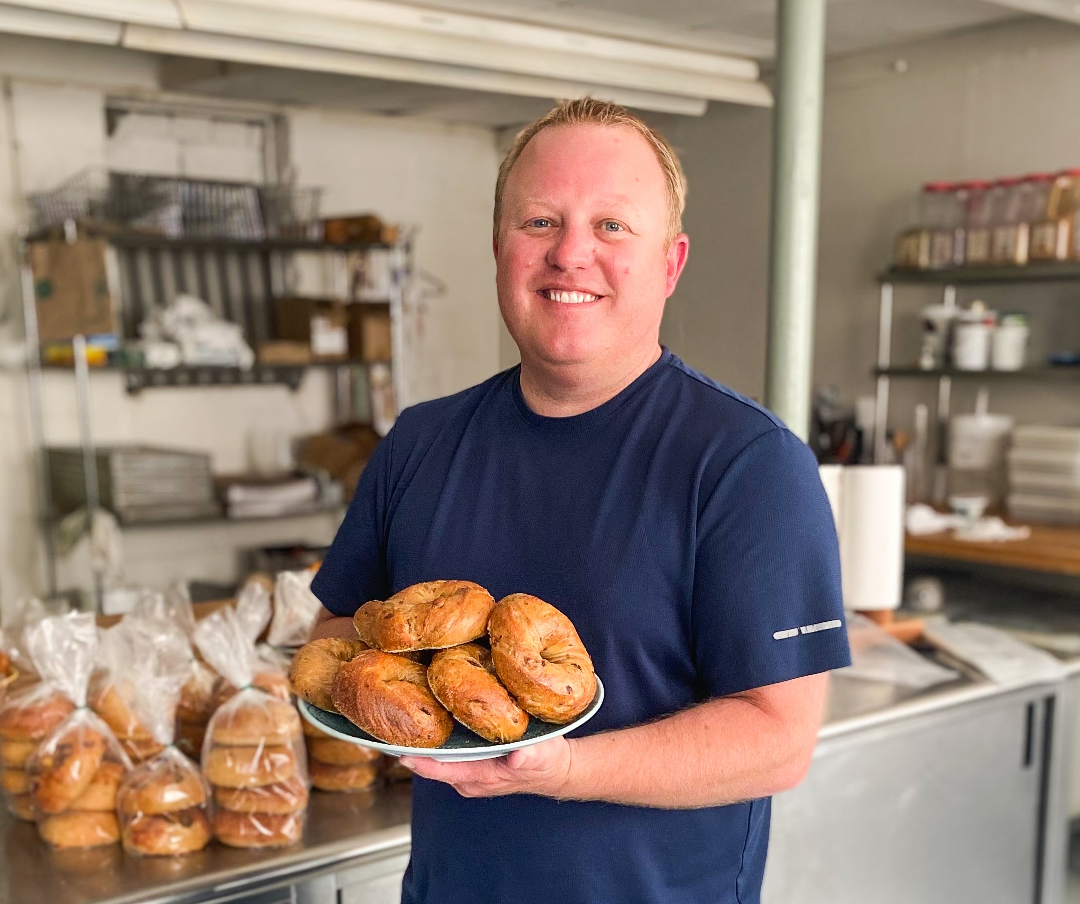 John Heintzberger holds bagels on a plate.