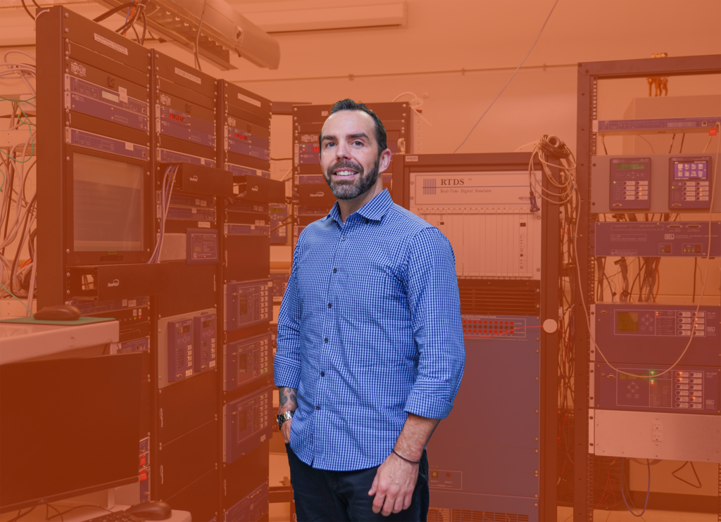 Cody Shepherd stands and smiles at the camera with an orange background.