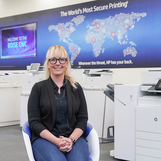 Cybersecurity student, Kris Pruett, standing in front of a sign that reads "The World's Most Secure Printing"