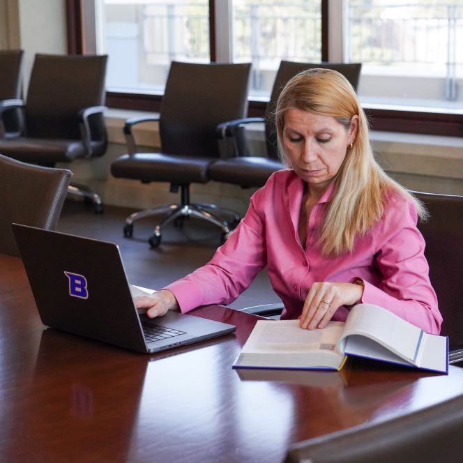 Student working at laptop with a textbook