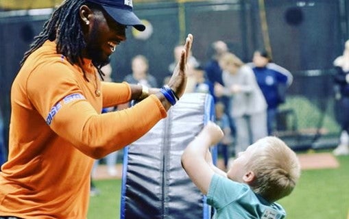 Alexander Mattison gives a high-five to a child on a football field