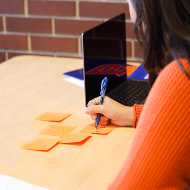 An ISC student taking notes using sticky notes while sitting on a desk