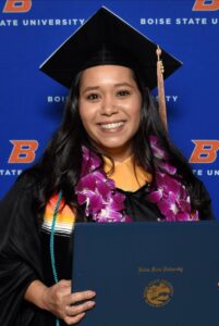 Magdalena Butler smiling for a graduation photo with her diploma.