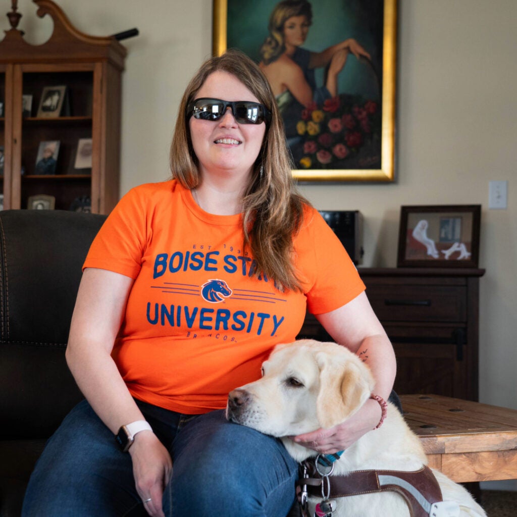 Boise State online Bachelor of Business Administration in Management student MaryBeth Clare sits with her guide dog, Hubble in her living room. 