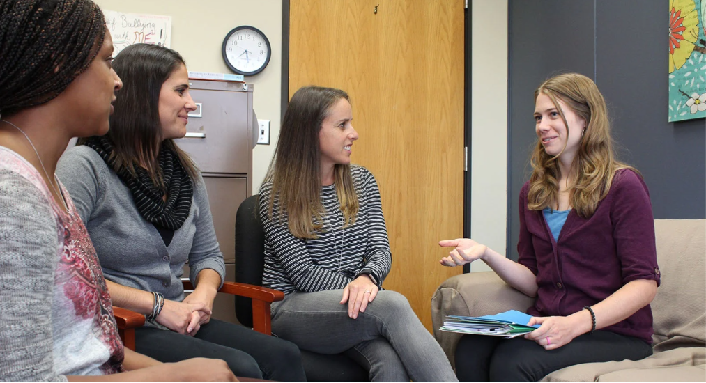 Counselor sitting in a room with a group of three students