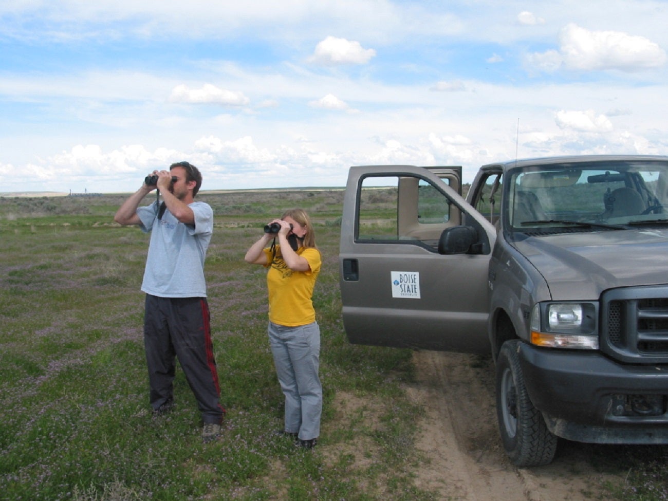 Two REU students using binoculars to survey for raptors