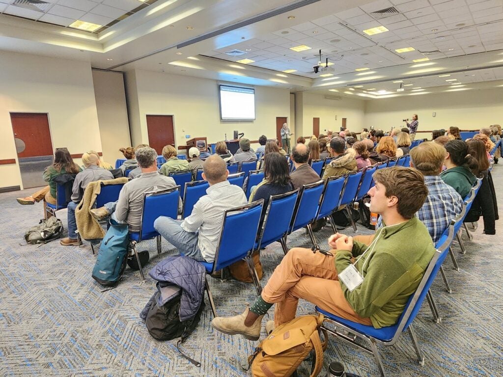 About 100 people seated listening to a presentation at the 2024 Morley Nelson Snake River Birds of Prey National Conservation Area Symposium