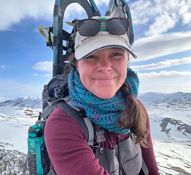 Portrait of professor Stephanie Galla with pack and snowshoes in arctic landscape