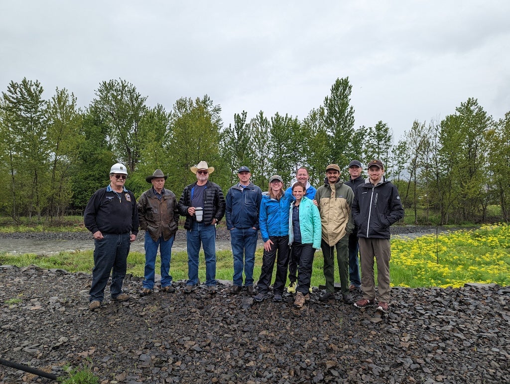 An image of 10 people standing by the river