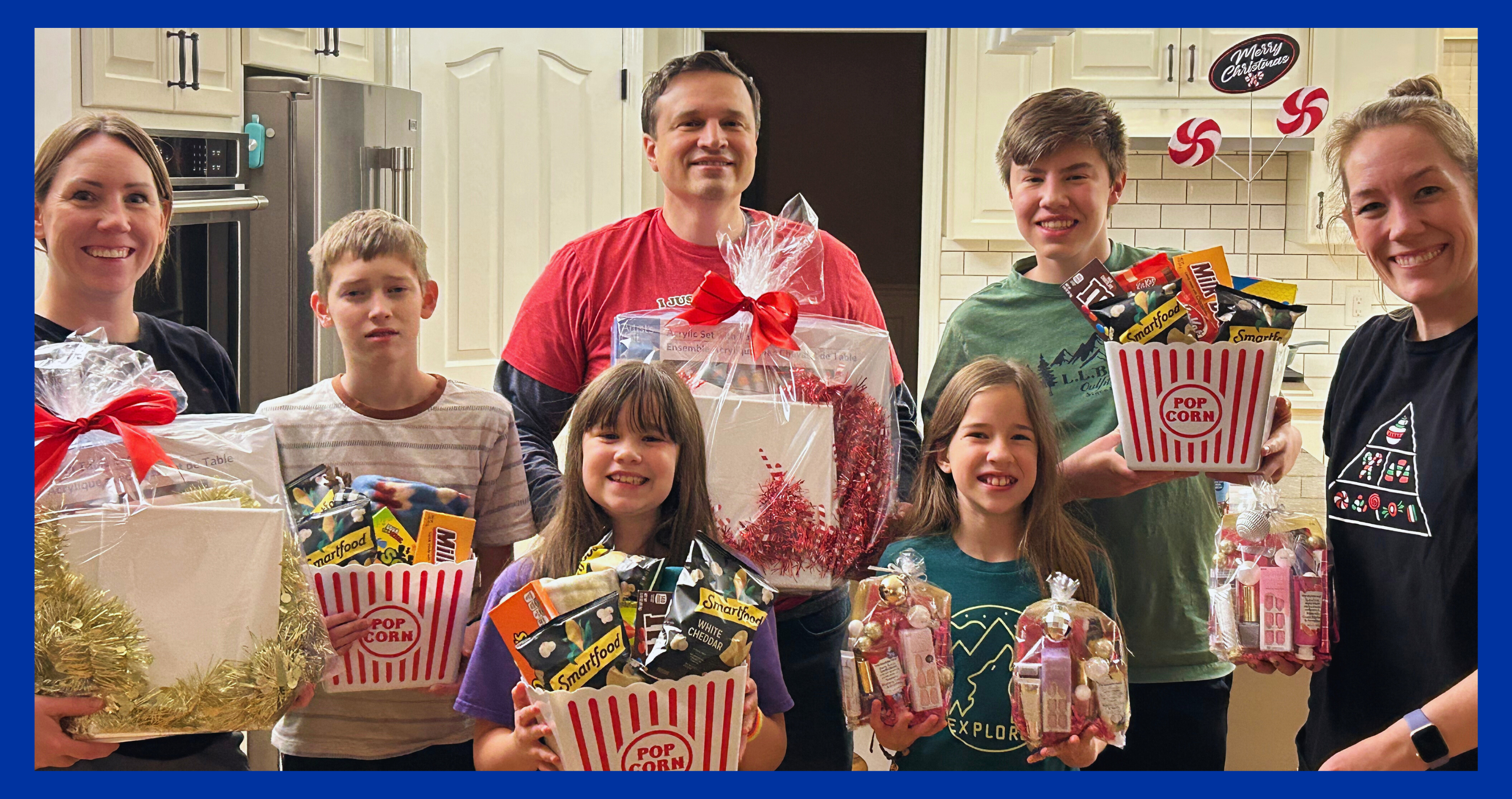 Cassie (R), Amanda (L-sister), Rob (brother-in-law), and family stand with Christmas gift baskets to support a local women's shelter.