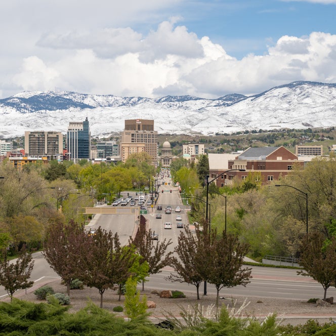 Daytime view of the Idaho Capital building with snow-capped mountains behind it.