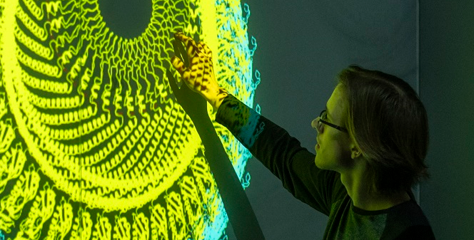 A person moves images on a screen at the Boise State Luminary