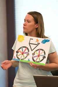 Student holding a painting of a bicycle