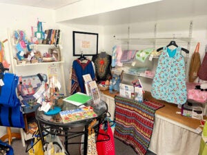 Different clothing made by refugees is hung and displayed on tables. 