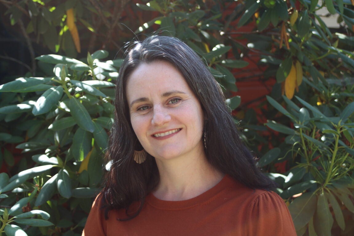 Headshot of a women next to a bush.