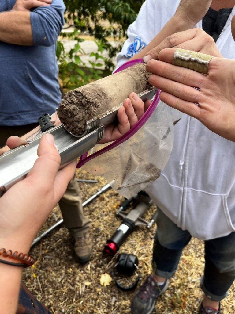 Close up view of people holding a soil core and talking about the soil color changes.