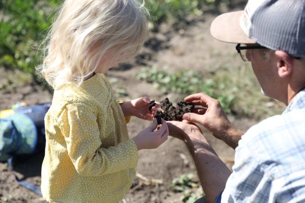 A man and a young child examine some soil